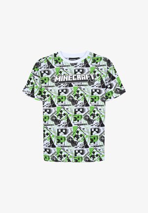 Koszulka z grafiką przedstawia czarny i zielony wzór z Minecraft, z pikselowymi postaciami i logo. Nosi ją osoba w szarych dżinsowych szortach i białych trampkach.