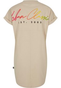 Robe beige à manches courtes avec poignets retroussés et texte coloré en écriture "Urban Classi EST. 2005" sur le haut du dos.