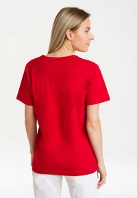 Red cotton t-shirt with short sleeves, round neckline, and a relaxed fit. Smooth texture with visible stitching along hems.
