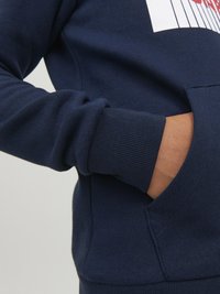 Felpa blu navy con polsini e orlo a costine, dotata di una tasca frontale e di una grande grafica rossa e bianca sul petto.