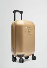 Valise rigide dorée avec une finition brillante, deux roues, poignée rétractable et un détail de logo à l'avant. Accents de fermeture éclair sur le côté.