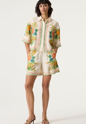 Korte mouwen shirt met bloemenborduursel en bijpassende korte broek in crème, met groene, oranje en blauwe accenten en een gestructureerde stof.