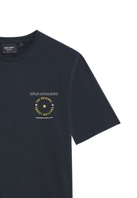 Marineblå bomulls T-skjorte med korte ermer. Har et sirkelformet gult logo design og teksten "LYLE ATHLETIC" på brystet.