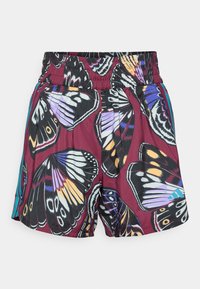 Bermuda scarlet dengan tali pinggang elastik, dihiasi dengan corak sayap rama-rama yang besar dan berwarna-warni dalam gabungan warna hitam, putih, ungu, dan kuning.