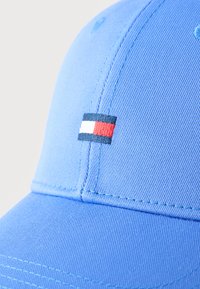 Φωτεινό γαλάζιο καπέλο μπέιζμπολ με ένα μικρό ορθογώνιο κεντητό λογότυπο σε ναυτικό μπλε, άσπρο και κόκκινο στην μ προστινή πλευρά.