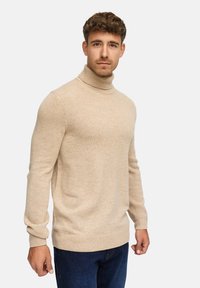 Tansin turtleneck-paita, joka on valmistettu pehmeästä, teksturoidusta materiaalista. Slim fit -malli, röyhelökaulus ja helma, yhdistetty tummaan sinisiin farkkuihin, joissa on yksinkertainen muotoilu.