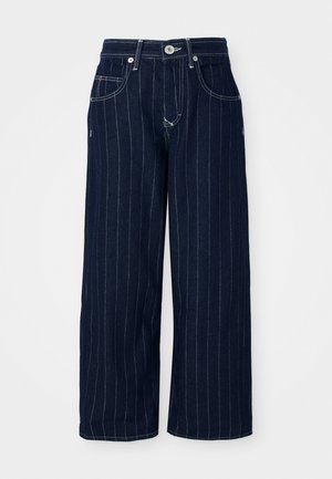 Jean large en denim bleu foncé avec des rayures blanches verticales. Comprend une fermeture à bouton, des passants de ceinture et des poches avant.
