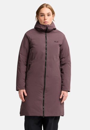 Vrouw draagt een lange mauve winterjas met capuchon en rits aan de voorkant, staand tegen een egale lichte achtergrond.