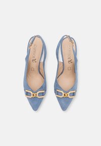 Siniset nahkaiset slingback-kengät, joissa on terävät varpaat. Edessä on kultaketjukiinnitys, ja sisäpohja on sileä ja vaaleanvärinen.