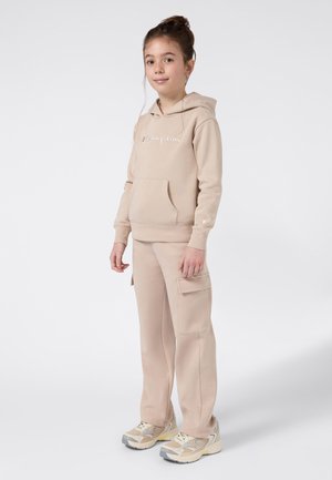 Beżowa bluza z kapturem z kieszenią kangurką i haftowanym logo, w połączeniu z pasującymi spodniami cargo z kieszeniami bocznymi oraz beżowymi sneakersami.