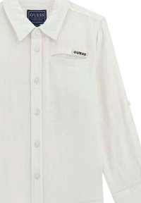 Camicia bianca button-up con tessuto testurizzato, dotata di colletto, bottoni frontali e taschino sul lato sinistro con etichetta del marchio.