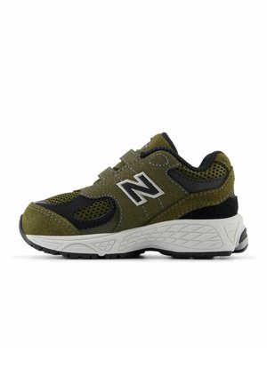 Chaussure de sport vert olive avec des accents noirs, matériaux en daim et en maille, semelle intermédiaire blanche épaisse, semelle extérieure en caoutchouc texturé, sangles réglables.