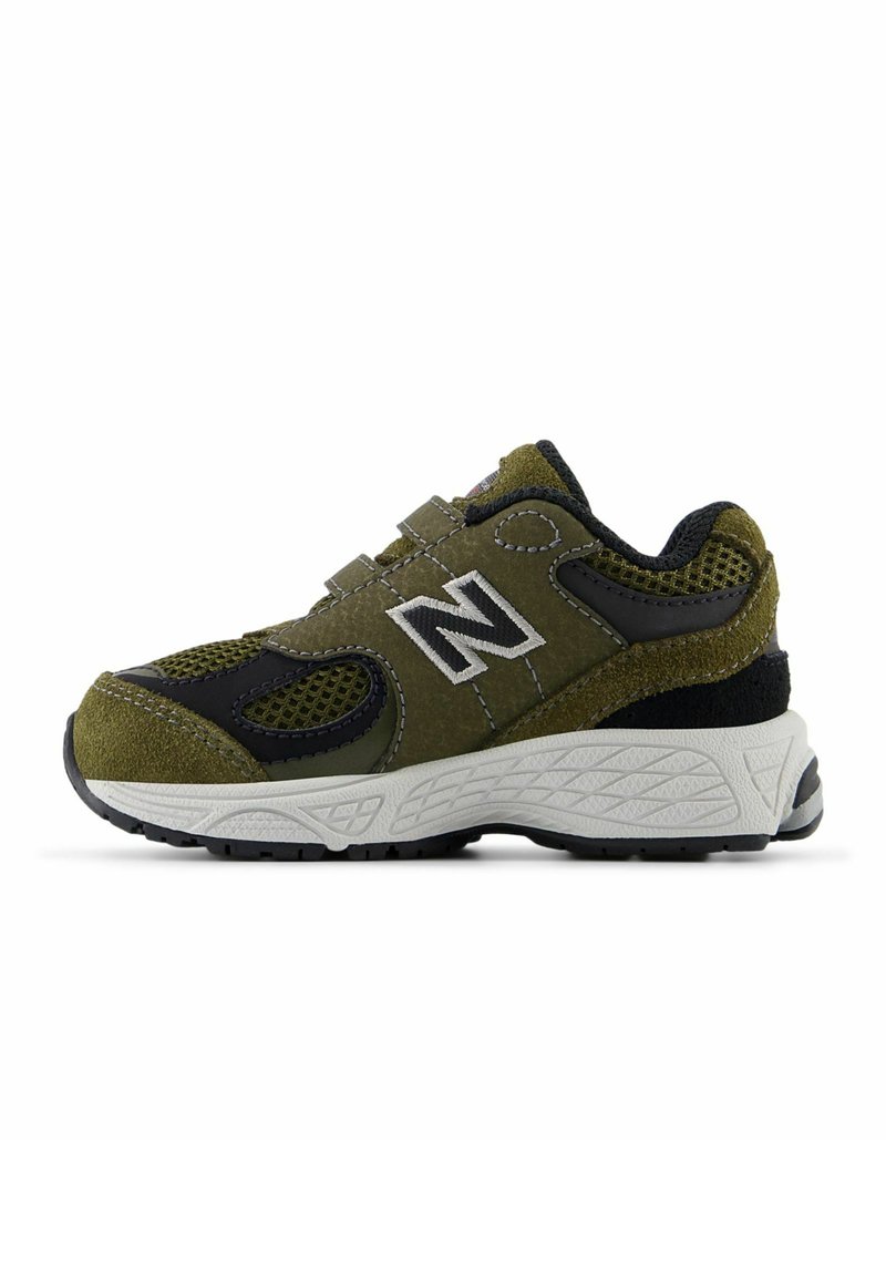 Olive green athletic shoe with black accents, suede and mesh materials, chunky white midsole, textured rubber outsole, adjustable straps.