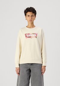 Krémová mikina s dlhým rukávom a uvoľneným strihom, s grafickým logom Levi's vo florálnom dizajne na prednej strane. Textúrovaná látka.