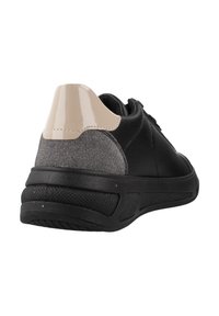Zapatilla negra con parte superior de cuero negro texturizado, acento de tela gris y capa de talón beige brillante. Presenta una suela de goma con tacos.