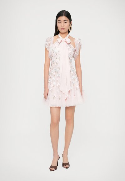 Ružové šifónové šaty s kvetinovou výšivkou a mašľou na krku. Volánové rukávy a krátky vrstvený lem. Hnedé sandále na podpätku s otvorenou špičkou.