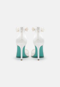 Sandali con tacco alto bianchi dal finish lucido, con suola turchese e dettaglio della cerniera posteriore decorato con perle. Design open toe.