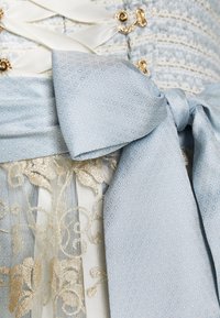 Robe bleu clair avec un tissu texturé à motif losange, un nœud décoratif et des accents dorés avec des détails en dentelle florale à l'ourlet.