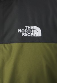 Tessuto nero e verde oliva con finitura testurizzata, caratterizzato dal logo ricamato bianco "THE NORTH FACE" e dal design della mezza cupola.