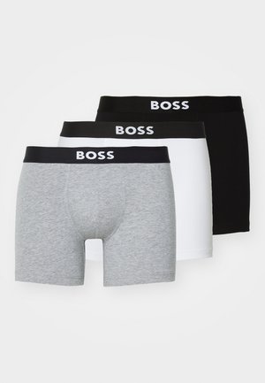 Trīs bokseršortu pāri: viens pelēks, viens balts un viens melns. Visiem ir melna jostasvieta ar baltu uzrakstu "BOSS".