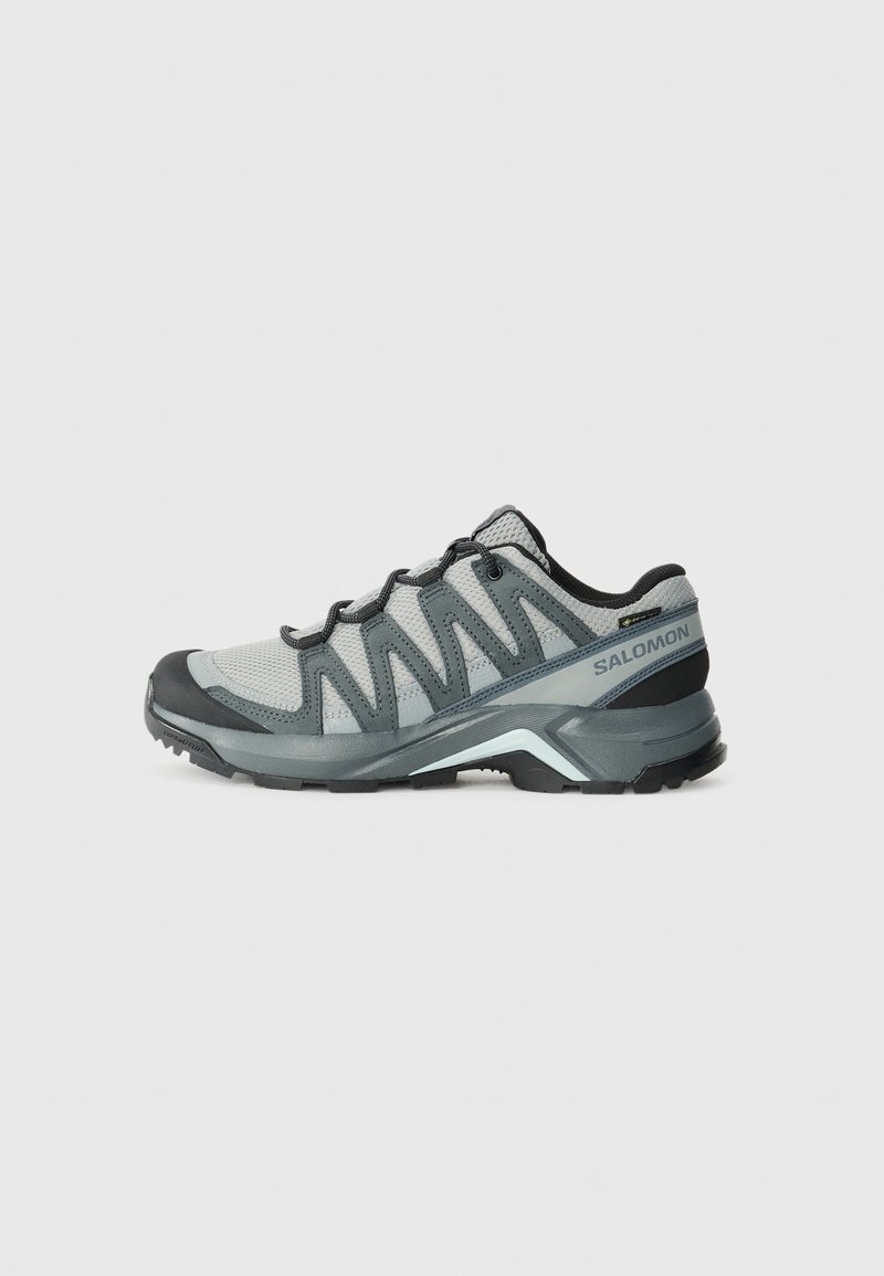 Leichte Wanderschuhe aus grauem Mesh mit dunklen Akzenten. Sie verfügen über eine strukturierte Laufsohle und eine gepolsterte Ferse für Komfort und Grip.