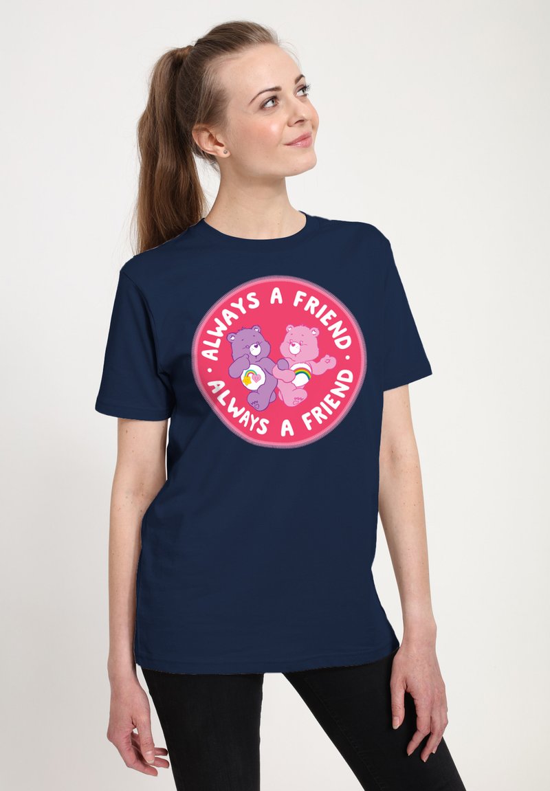 Camiseta de color azul marino con un gráfico circular que presenta dos osos de dibujos animados, uno púrpura y uno rosa, rodeados del texto "Siempre un Amigo."