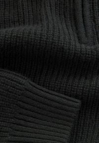 Schwarzer Strickstoff mit geripptem Muster, das dicke und dünne Linien zeigt und ein weiches, warmes Aussehen hat.
