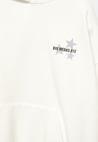 Vit hoodie i mjukt tyg, med en framficka och tryckt texten "BYE MEANS BYE" med tre grå stjärnor i olika storlekar.