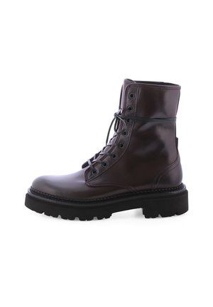 Botte en cuir marron à lacets avec un bout rond, une semelle en caoutchouc épaisse et des œillets en métal. Texture lisse avec un détail de bord cousu.