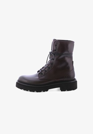 Botte en cuir marron à lacets avec un bout rond, une semelle en caoutchouc épaisse et des œillets en métal. Texture lisse avec un détail de bord cousu.