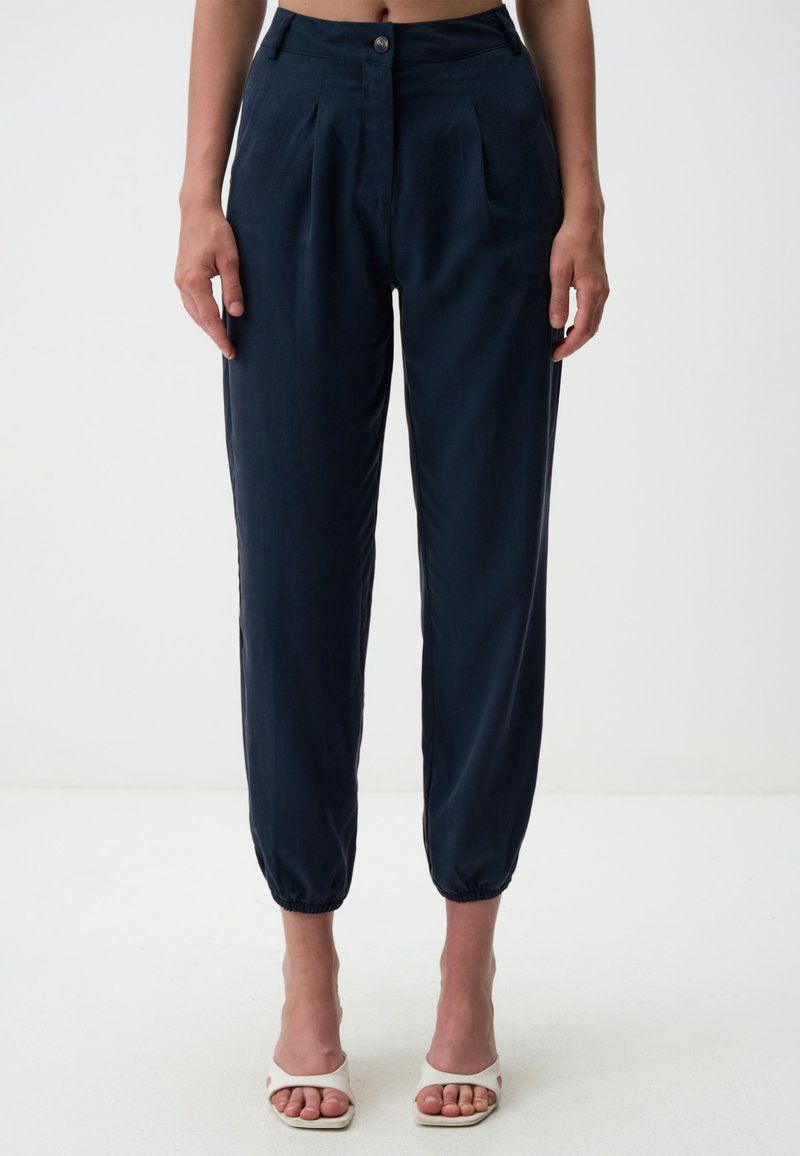 Marineblaue, taillierte Hose mit gefaltetem Vorderteil und elastischen Bündchen. Aus einem glatten Material gefertigt, mit einem einzelnen Knopfverschluss und seitlichen Taschen.