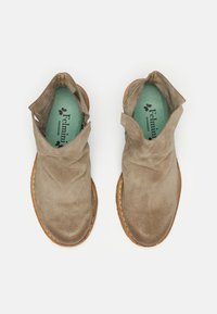 Stivaletti in suede beige alla caviglia con punta arrotondata, lati aperti e cerniera. Presentano una suola texturizzata marrone chiaro e una soletta verde con branding.