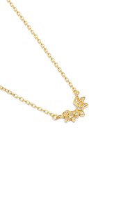 Collier en or avec une chaîne et un pendentif décoratif en forme de feuille, incrusté de pierres claires, réfléchissant la lumière.