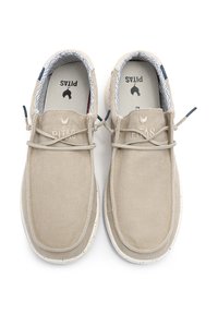 Beige canvas shoes with a textured finish, elastic laces, and white speckled rubber soles. Interior features a patterned lining.