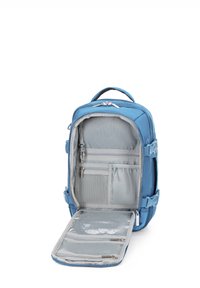 Modrá batoh s pevným vnějším povrchem, šedým vnitřkem, několika kapsami a zipy. Má ploché dno pro stabilitu, když je otevřený.