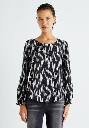 Black and white long-sleeve blouse featuring an ikat pattern, round neckline, and gathered cuffs, made from lightweight fabric.
