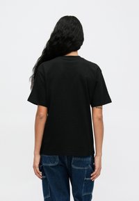 Must must t-särk lühikeste varrukatega, ümar kaelus ja lihtne, puhas disain. Sujuv tekstuur, nähtavaid mustreid ega logo ei ole.