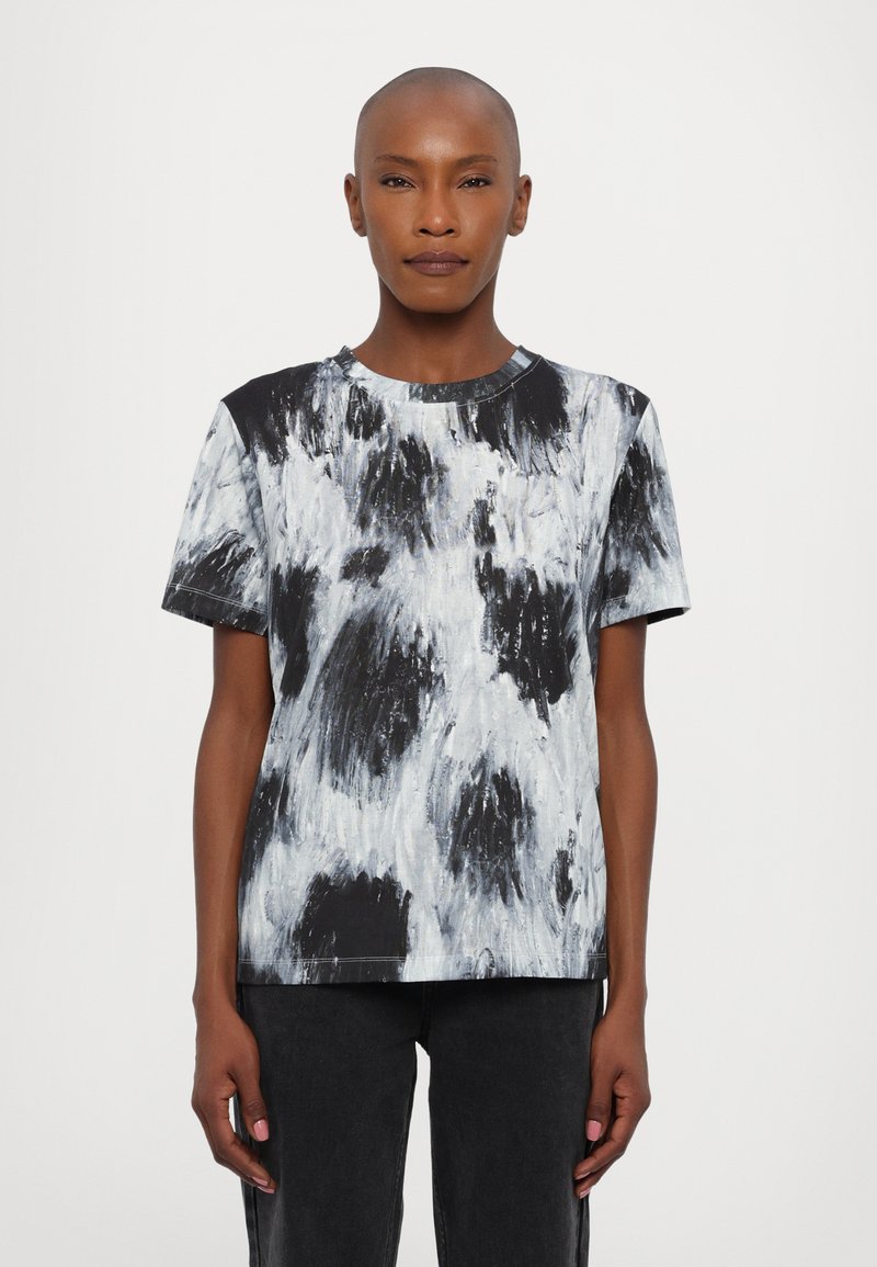 T-shirt à manches courtes avec un motif abstrait noir et blanc, un col rond et une coupe décontractée. Fabriqué en tissu doux et texturé.