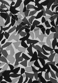 Black and white fabric with an abstract, geometric pattern featuring irregular shapes in varying shades and textures.