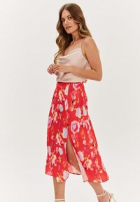 Květinová midi sukně v odstínech červené a růžové, s bočním rozparkem, hebkým povrchem a přiléhavým pasem. V kombinaci s lehkým saténovým topem.