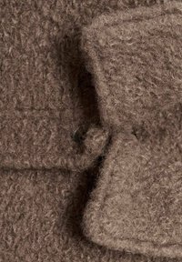 Țesătură texturată de culoare maro, cu un aspect pufos și moale. Dispune de un sistem de închidere cu nasture și un design cu clapetă suprapusă.