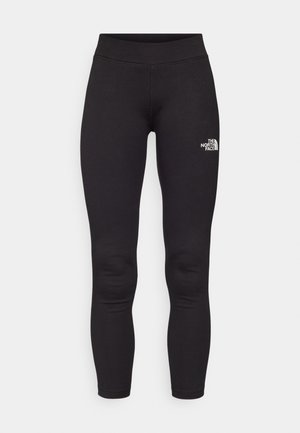 Black athletic leggings made of stretch fabric. Features a high waistband and a small white logo on the left thigh. Smooth texture.