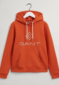 Sweat à capuche orange en tissu doux, avec une poche avant, des cordons blancs et un logo GANT blanc bien visible sur la poitrine.