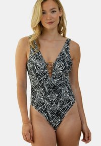 Maillot de bain une pièce noir et blanc avec un motif de feuilles, présentant un décolleté en V profond et des accents dorés en forme d'anneau à l'avant.