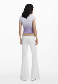 Top morado degradado de manga corta con un detalle de nudo en la parte posterior, combinado con jeans blancos de campana que tienen costuras laterales y un cinturón con tachuelas.