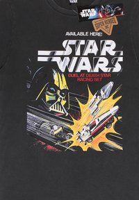 Sort bomulds T-shirt med et farverigt grafik af Darth Vader, racerbiler og "Star Wars" tekst. Fed, livlig illustration med detaljer.
