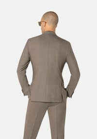 Hellbraunes maßgeschneidertes Anzug mit einem eleganten Design, strukturiertem Stoff, geflammten Revers und schlanken Hosen. Die Rückansicht zeigt maßgeschneiderte Linien und Taschen.
