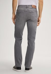 Pantaloni in denim grigio con vestibilità dritta, due tasche posteriori con patta e un'etichetta del marchio in pelle marrone in vita. Tessuto testurizzato.