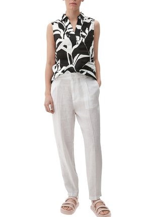 Haut sans manches à motifs noir et blanc, pantalon en lin gris clair et sandales pâles. Le haut présente un col et une coupe décontractée.