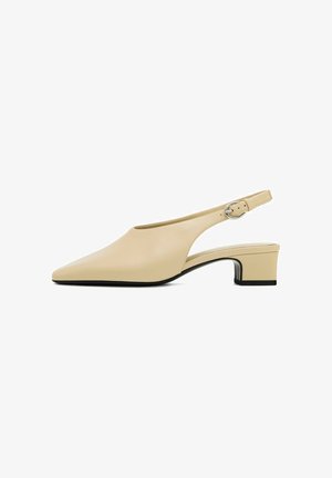 Beige leather slingback shoe with a pointed toe, a low block heel, and a circular buckle on the adjustable strap. Smooth texture.